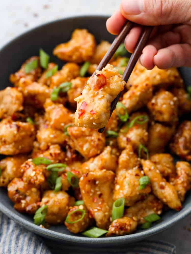 A piece of chicken being picked up with chopsticks.