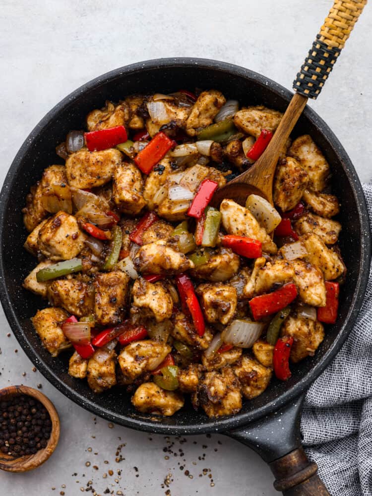 If you want to add a burst of flavor to weeknight dinners, this Chinese-inspired black pepper chicken is the perfect recipe to try! With its amazing homemade sauce, each bite is packed with savory, peppery, and slightly tangy flavors that will leave your mouth watering. Top-down view of black pepper chicken in a black skillet.