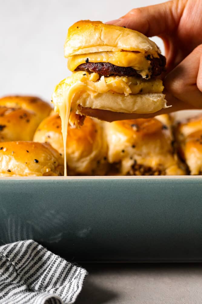Picking up a breakfast slider out of a casserole dish.