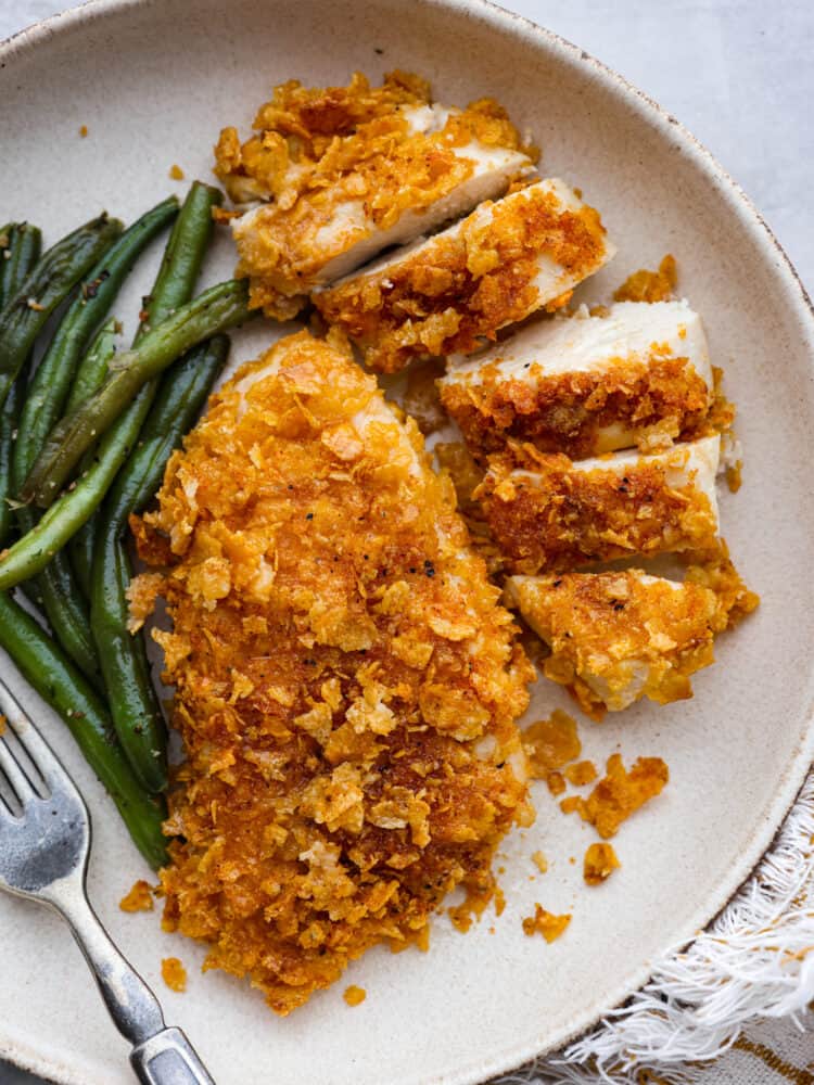 Nachos chicken and green beans on a white plate.