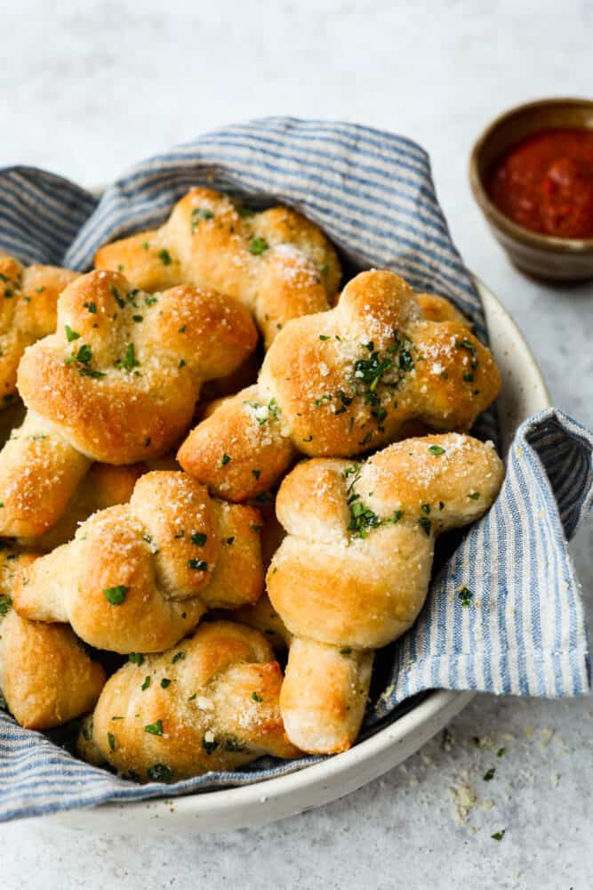 Hero image of homemade garlic knots in a white serving bowl.