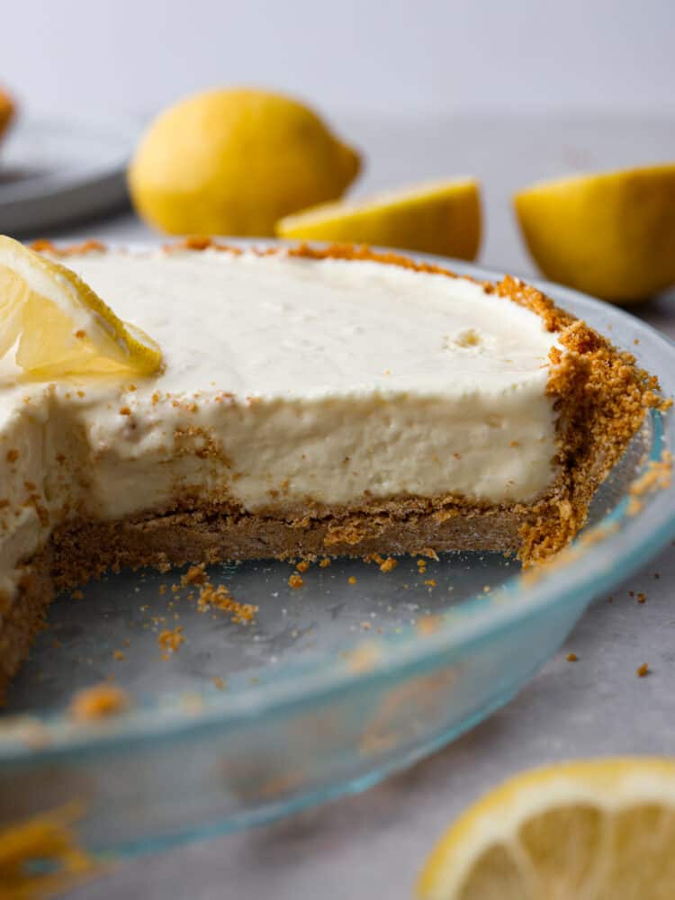 A whole lemonade pie with a slice cut out of it.
