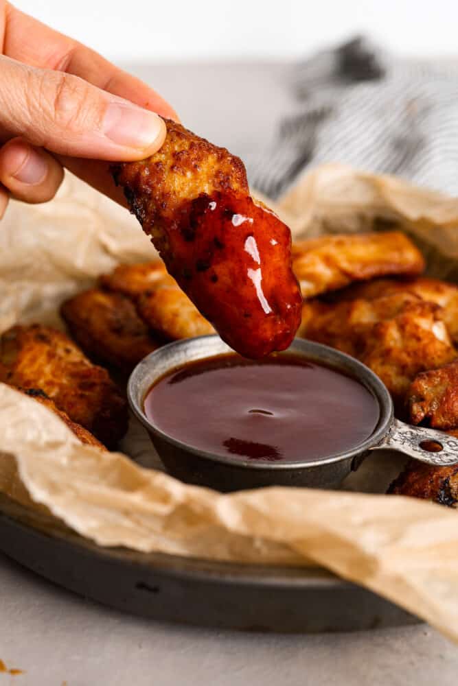 Dipping a chicken wing into mumbo sauce.