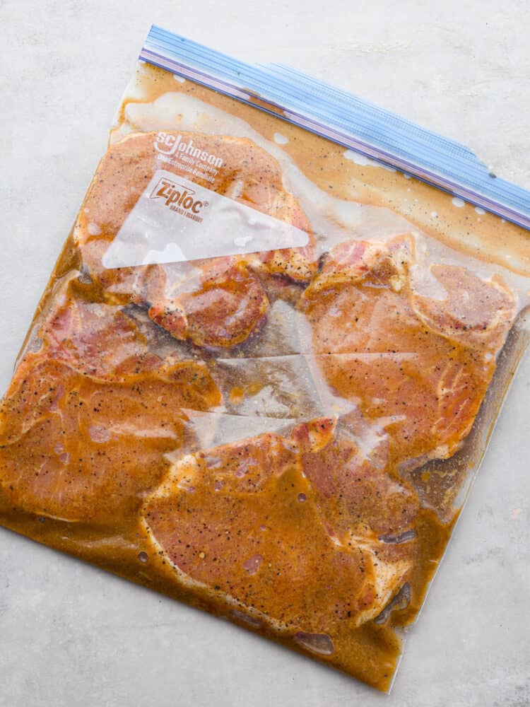 4 pork chops marinating in a Ziploc bag.