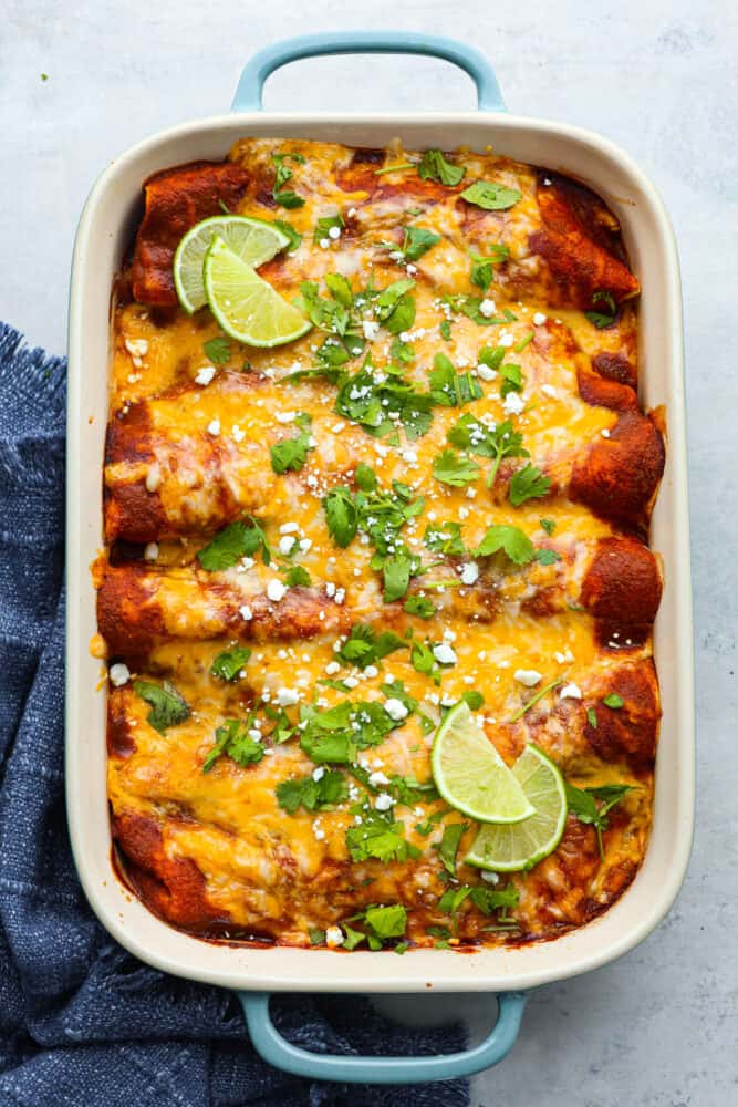 A blue and white casserole dish filled with baked enchiladas.