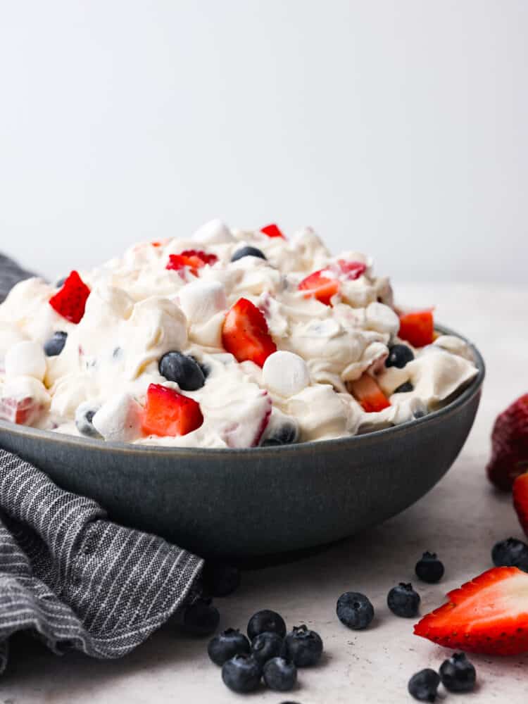 Red, white, and blue cheesecake salad in a black bowl.