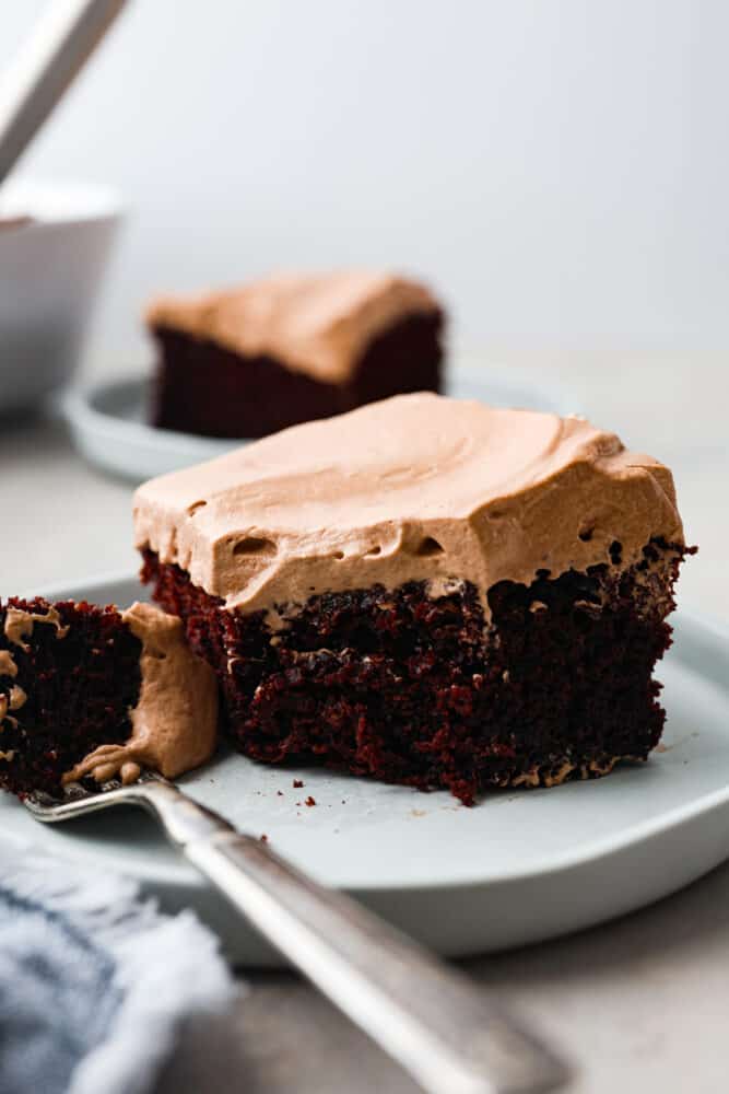 A slice of wacky cake on a plate with a fork and a bite take out. 