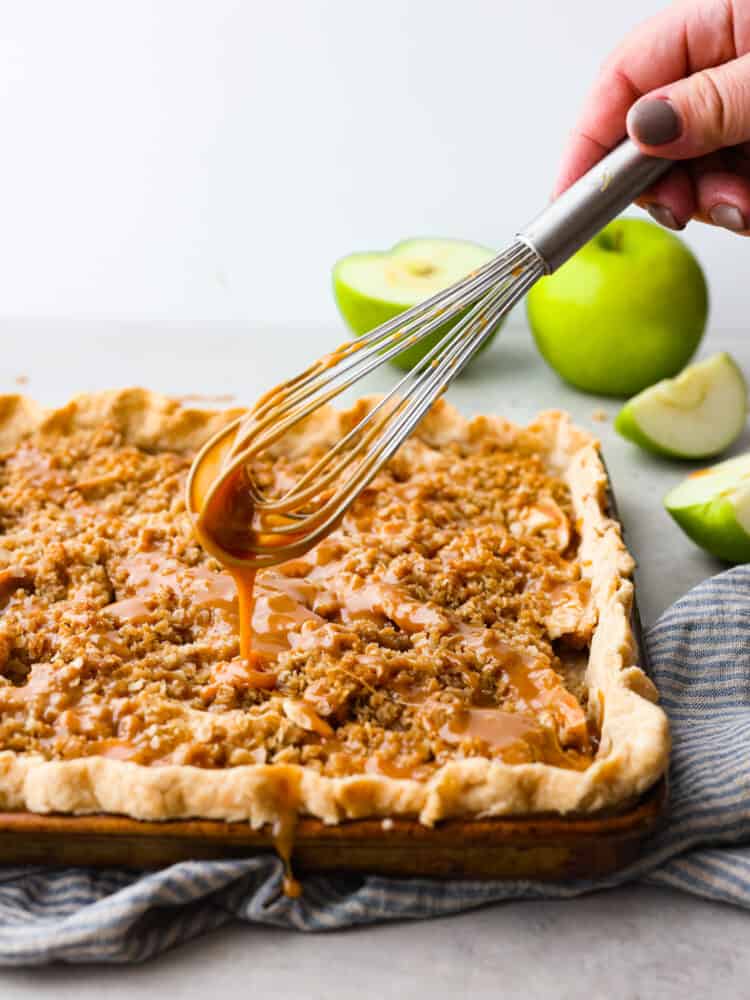 A whisk drizzling caramel onto the slab pie. 