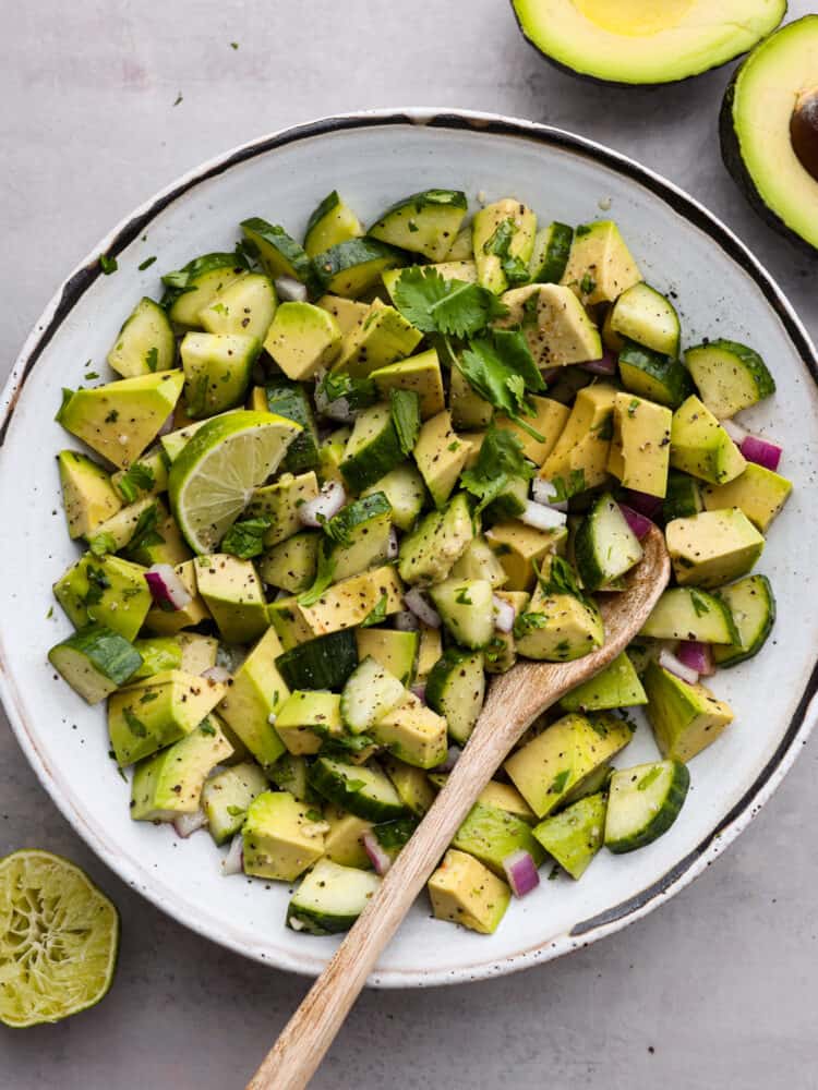 Top-down view of cucumber and avocado salad in a white bowl.