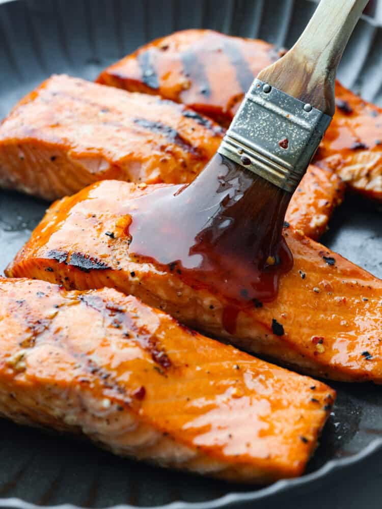 A basting brush basting salmon with firecracker sauce. 