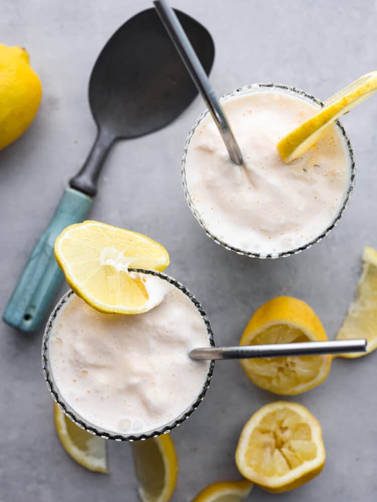 The top view of a frosted lemonade with lemon sliced scattered around the cup. 