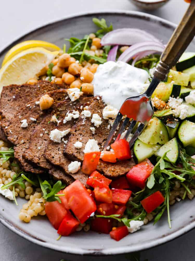 Taking a bite of gyro meat with a fork.