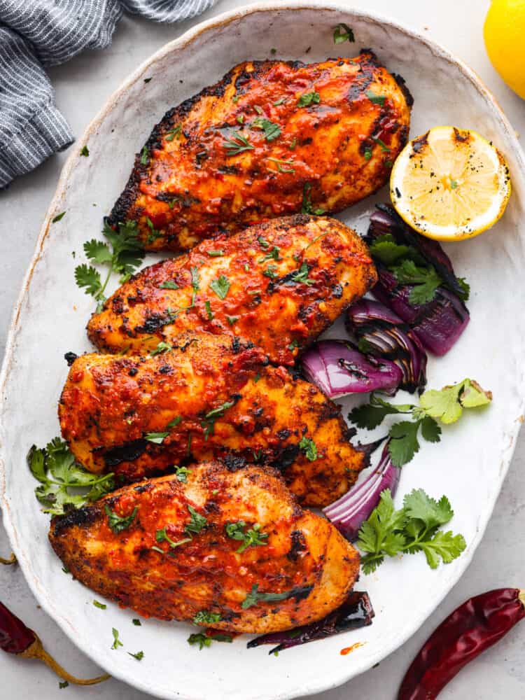4 pieces of harissa chicken served with vegetables and half a lemon.