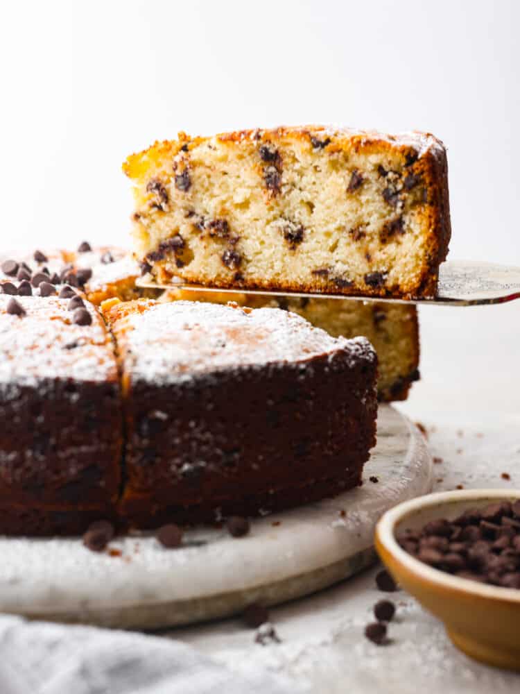 A slice of chocolate chip ricotta cake being served with a metal spatula.