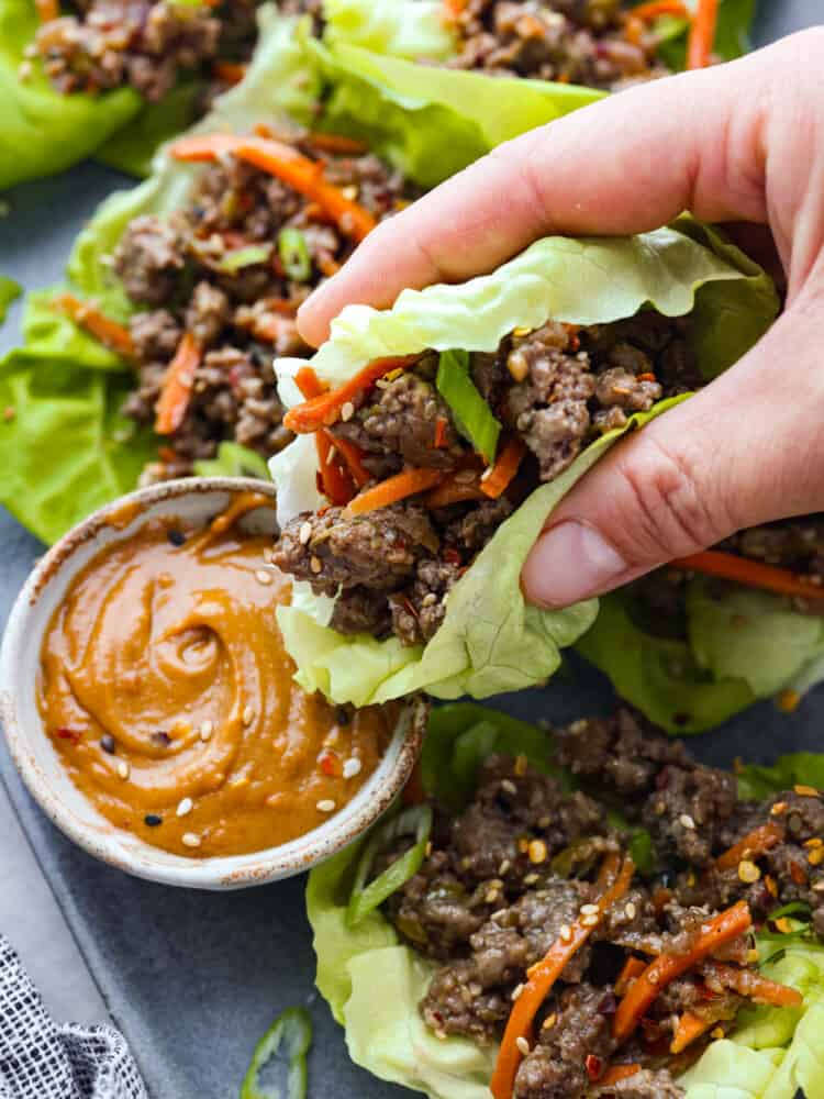 Dipping a lettuce wrap into peanut sauce.