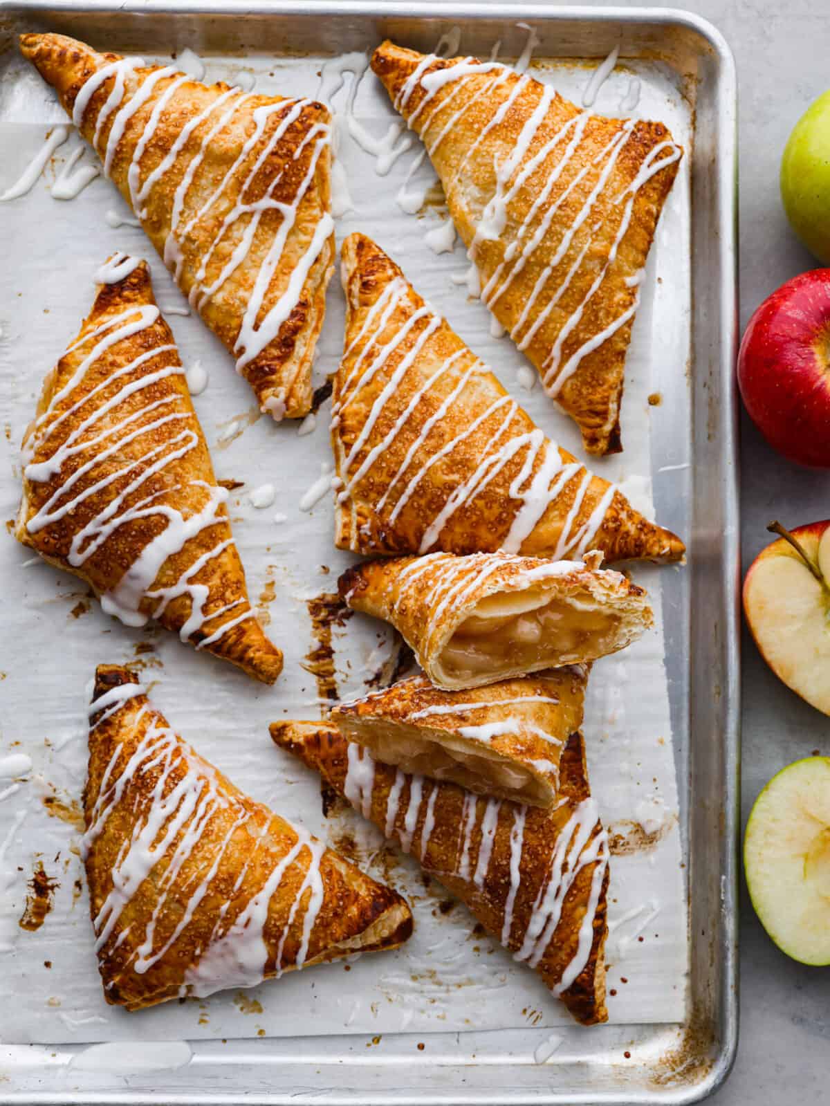 The top view of apple turnovers on a baking sheet with parchment paper. 