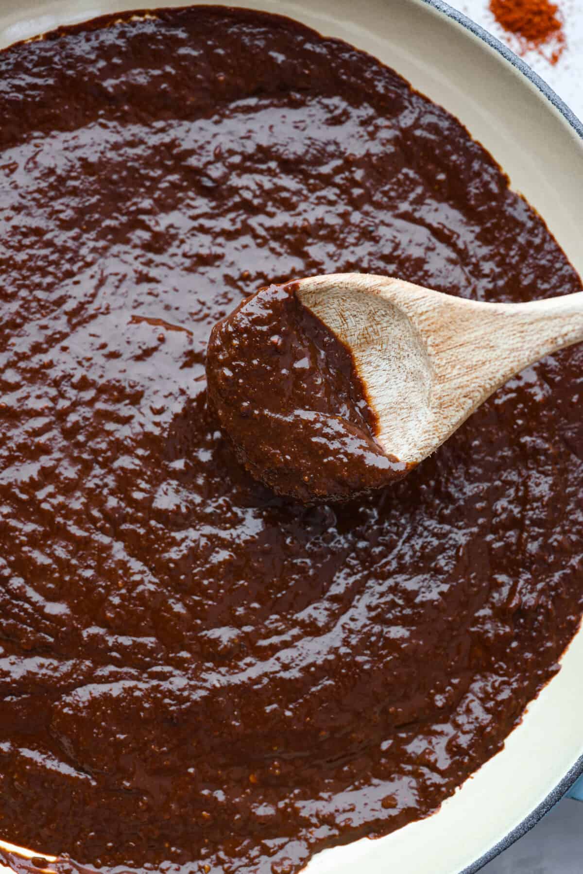 Closeup of mole sauce being stirred with a wooden spoon.
