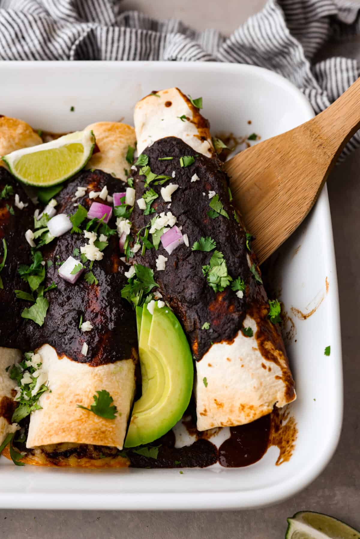 One enchilada being served with a wooden spatula.