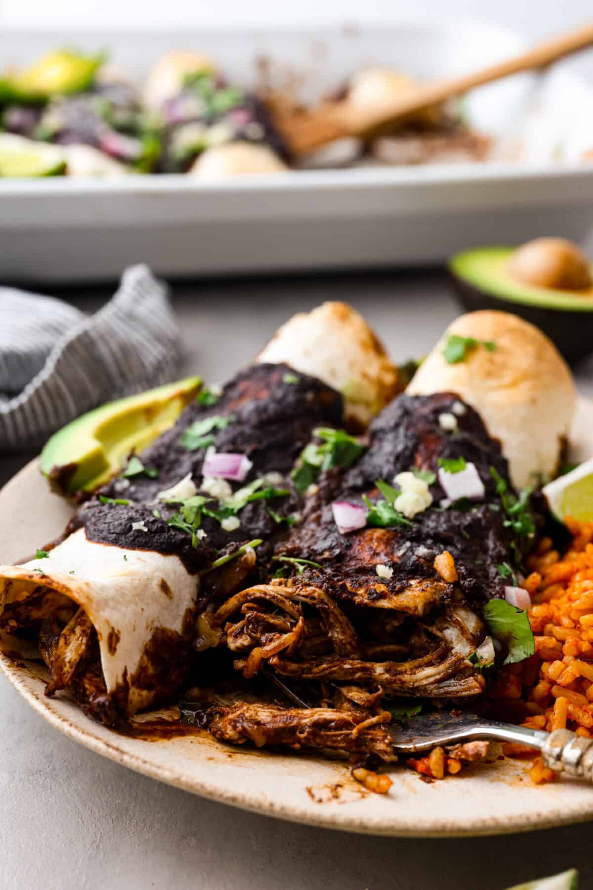 Two enchiladas covered in mole sauce.