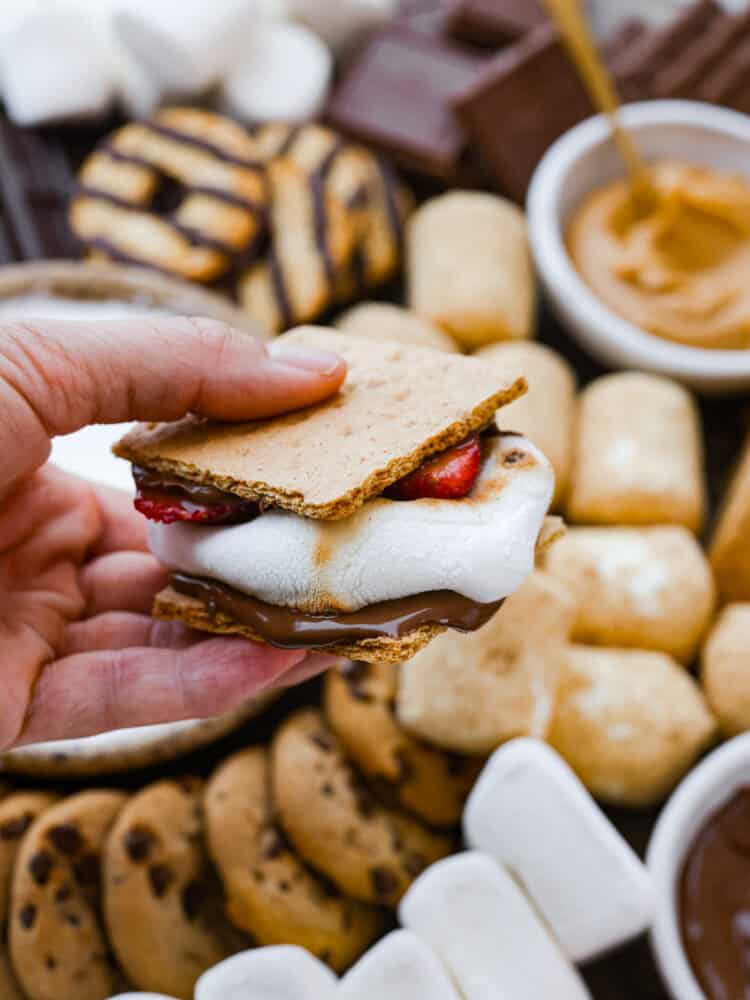 A s'more being held is someone's hand. 