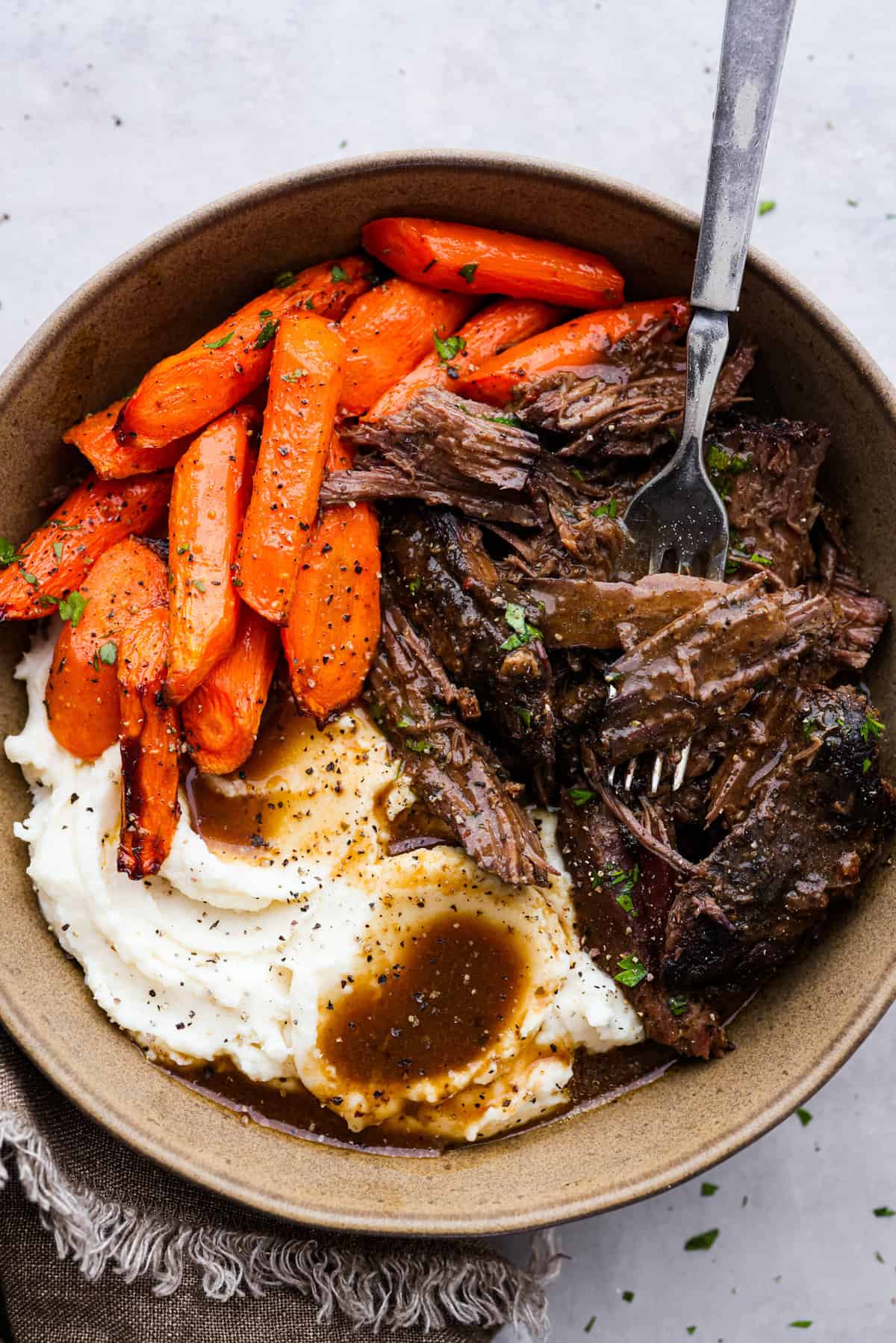 Shredded pot roast served with carrots and mashed potatoes.