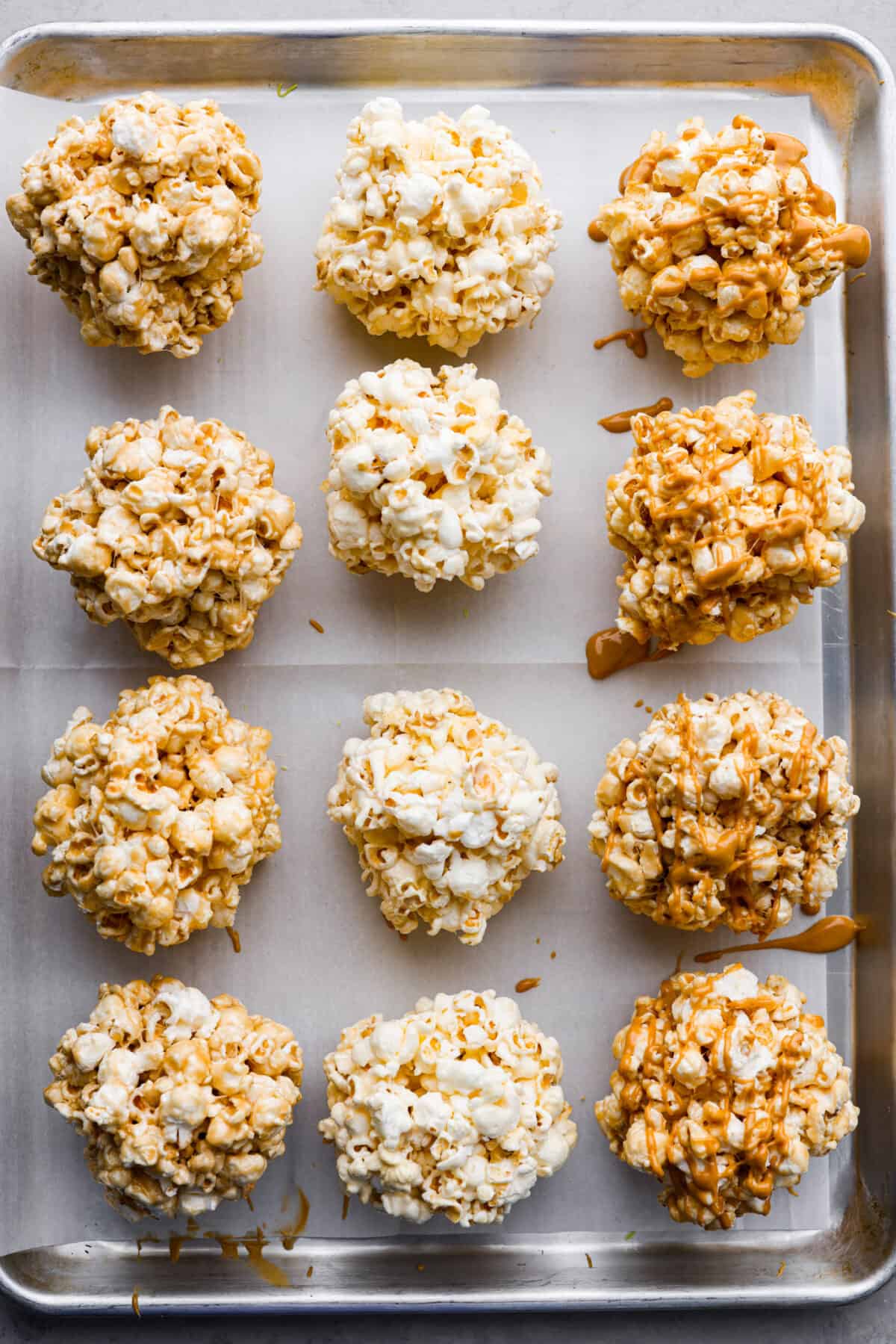 Top-down view of the popcorn balls on a parchment paper-lined baking sheet.