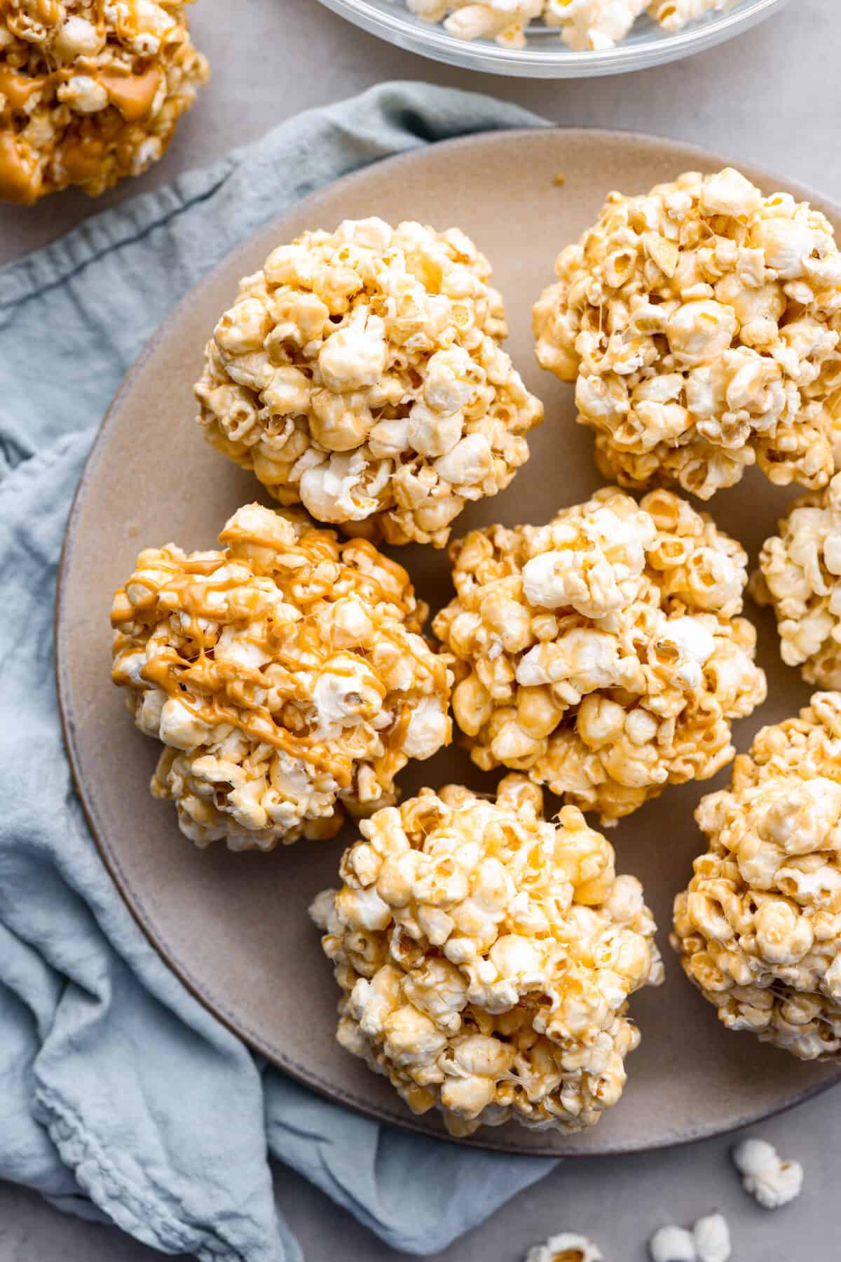 Marshmallow, caramel, and peanut butter popcorn balls on a gray plate.