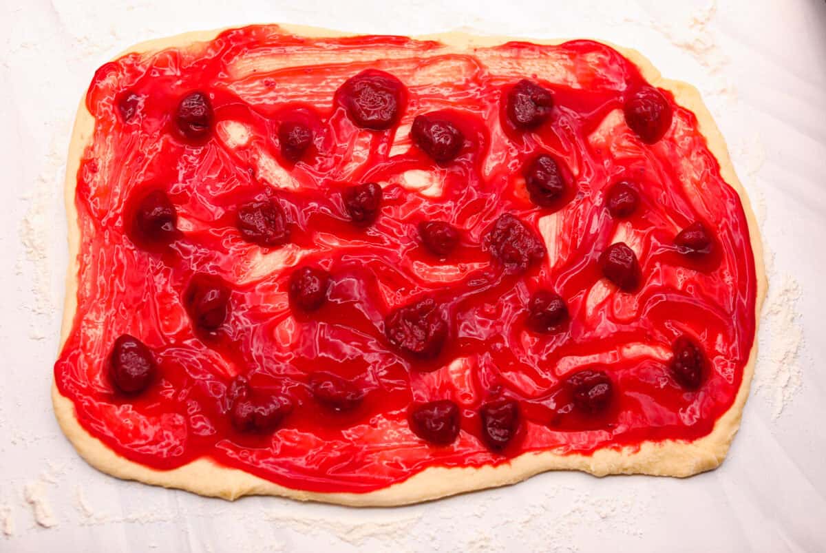 Strawberry pie filling spread out over the rolled out dough. 