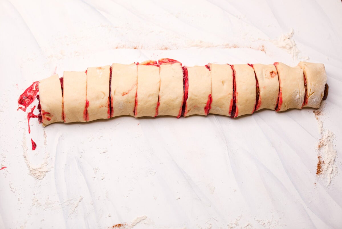 Dough log rolled up and cut into sliced, unbaked strawberry cinnamon rolls. 