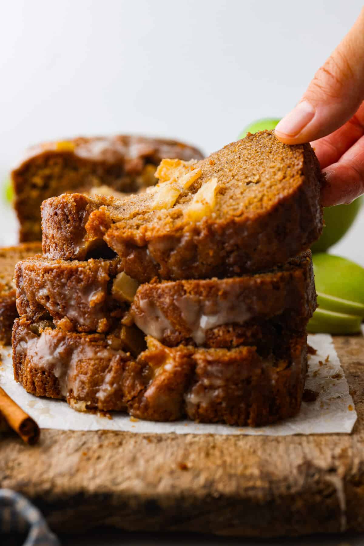 3 slices of apple bread stacked on top of each other, and one being picked up.