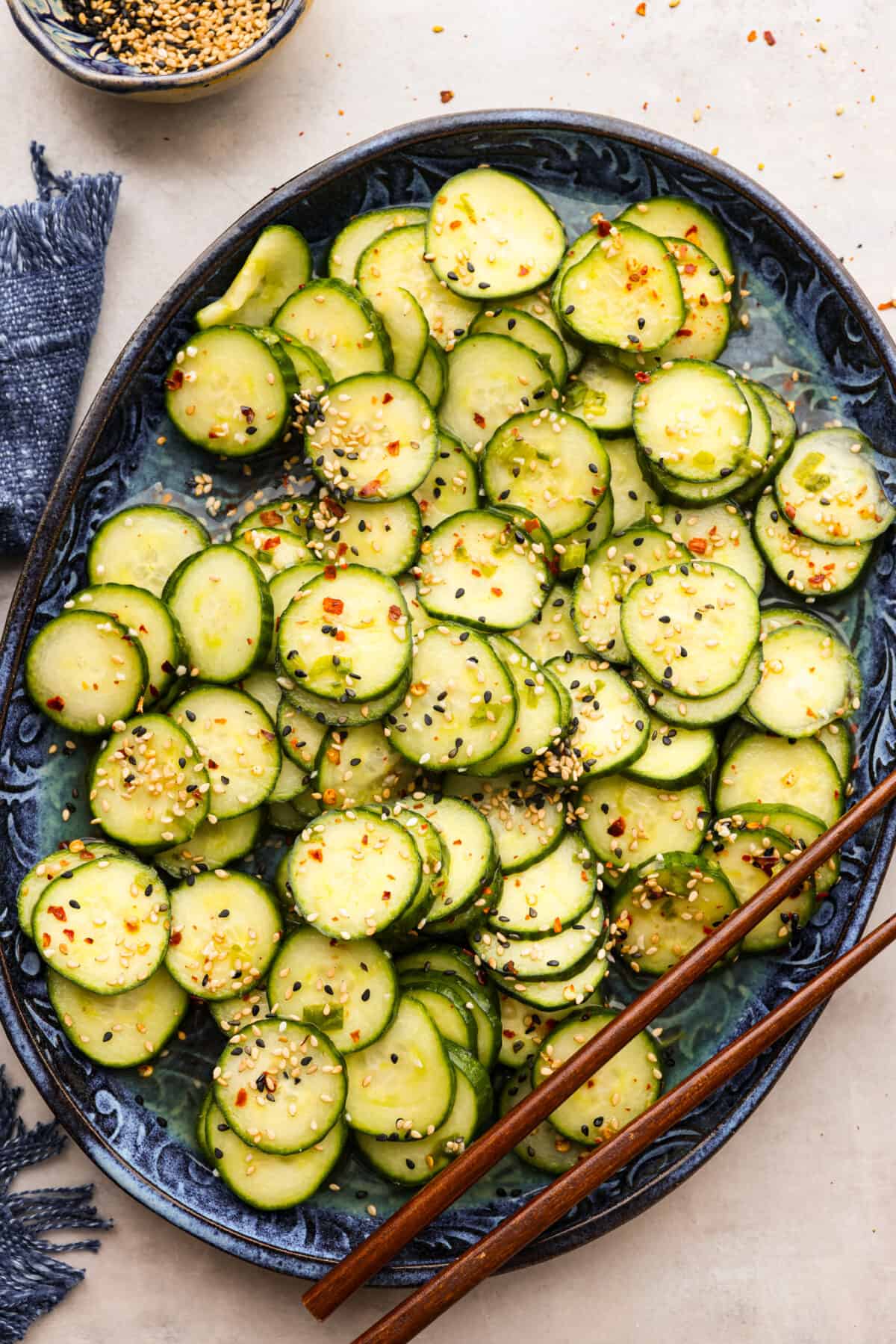 A platter of Asian Cucumber Salad with a pair of chopsticks on the side. 