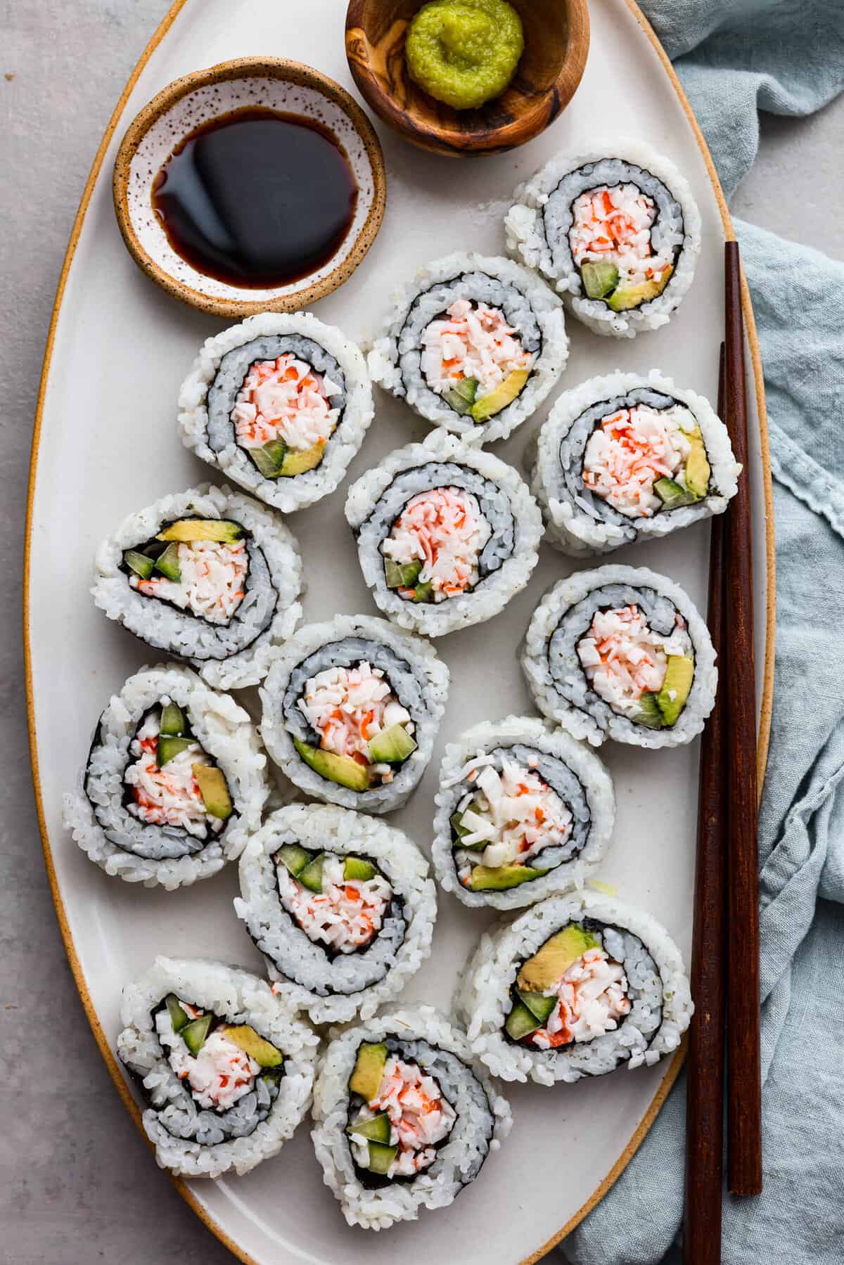 California rolls served on a large serving dish with soy sauce for dipping.