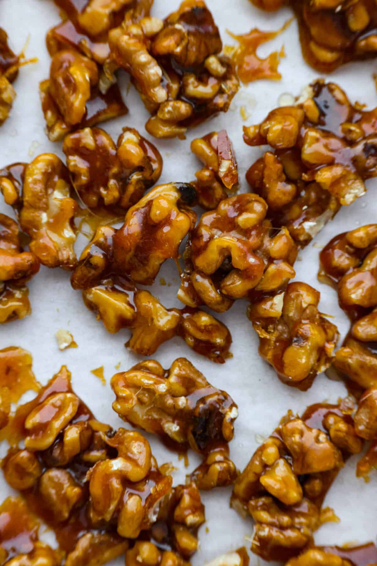 A close up of candied walnuts on parchment paper. 