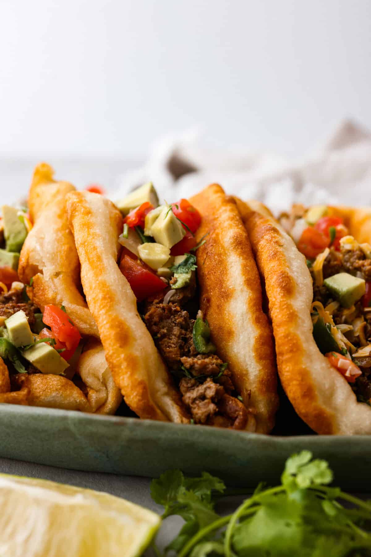 Closeup of 3 chalupas filled with beef and vegetables.