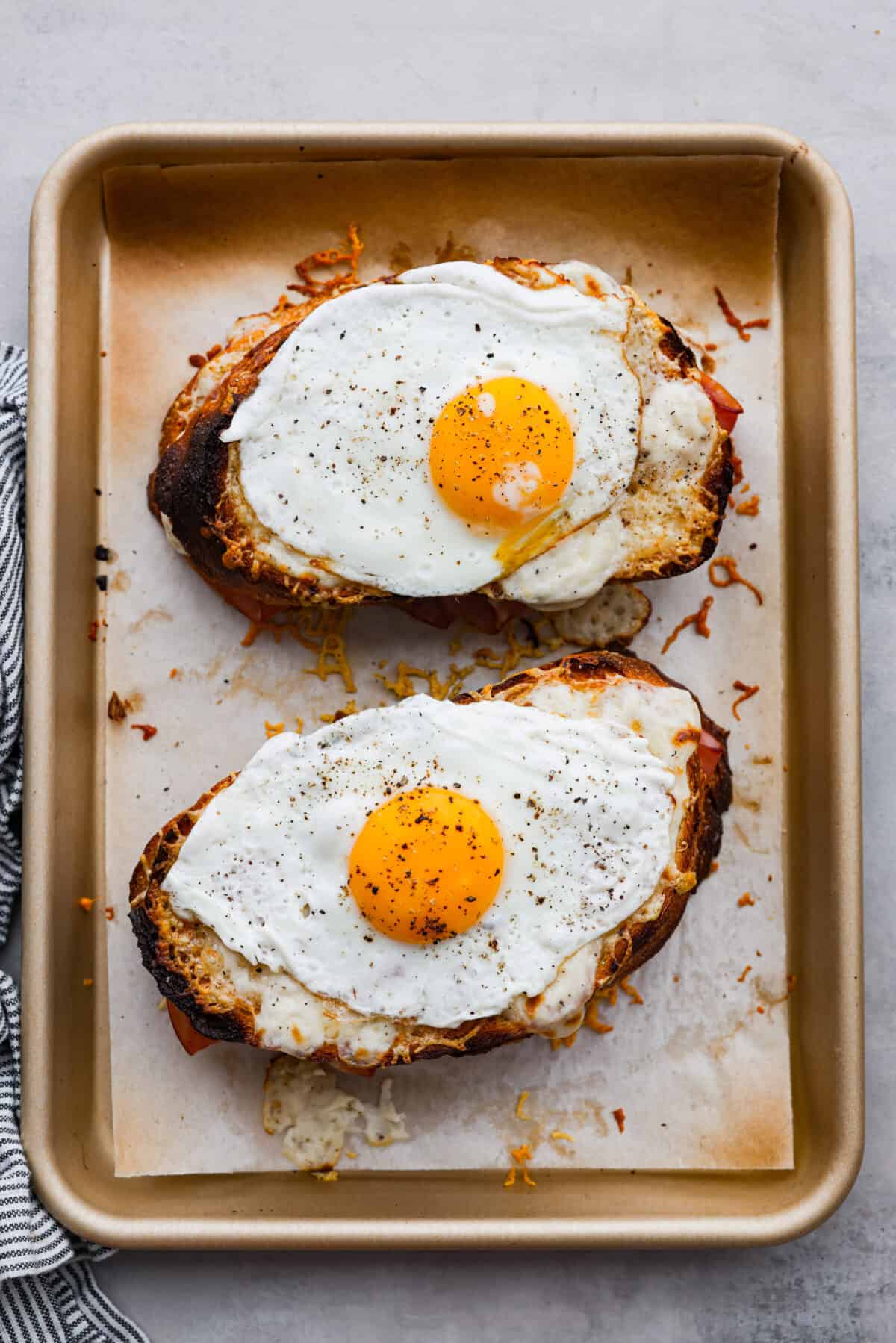 Top-down view of 2 sandwiches topped with fried eggs.