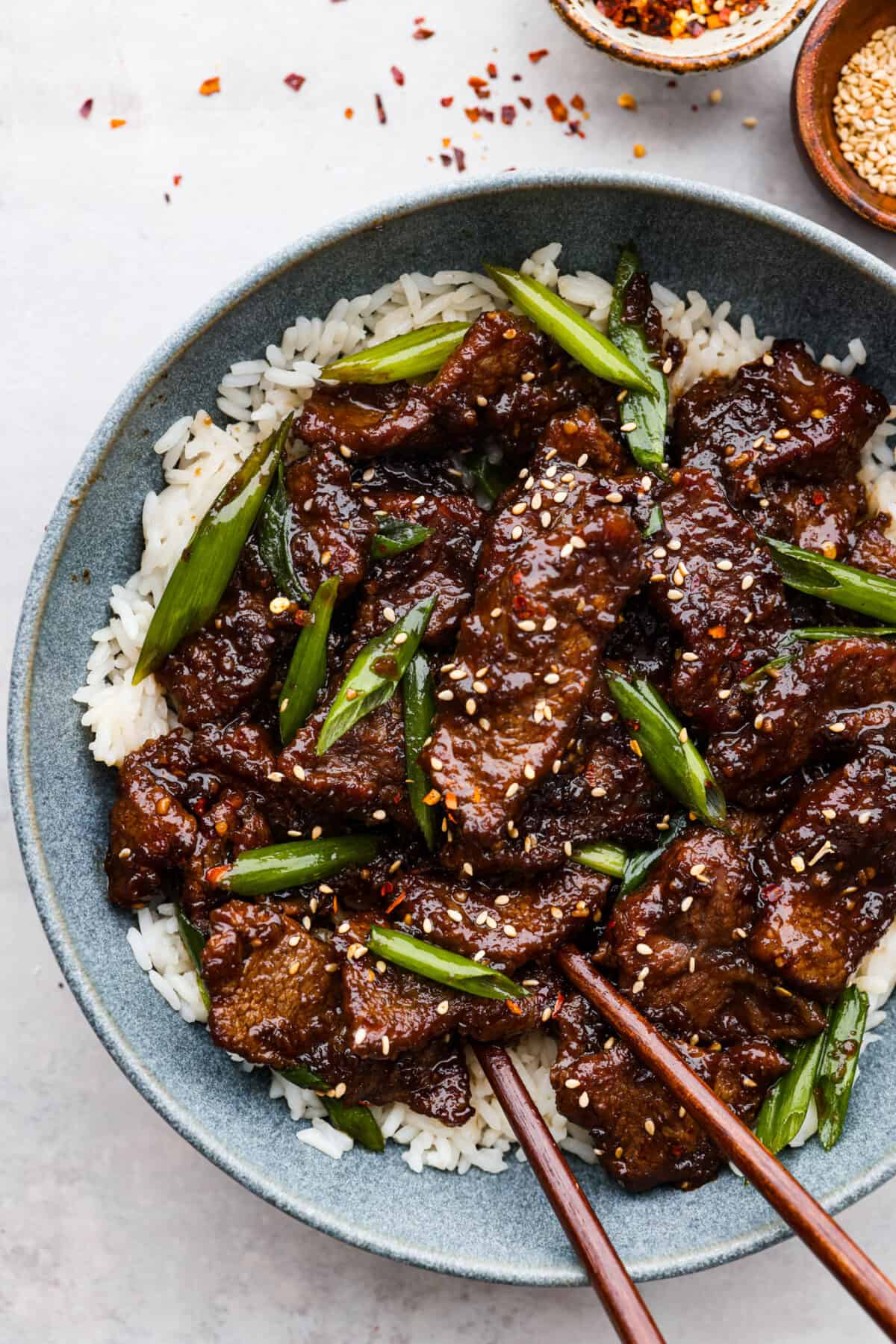 Mongolian beef served over rice in a blue bowl.