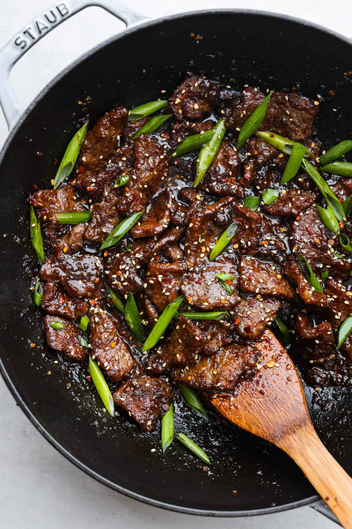 Top-down view of cooked beef and green onions in a skillet.