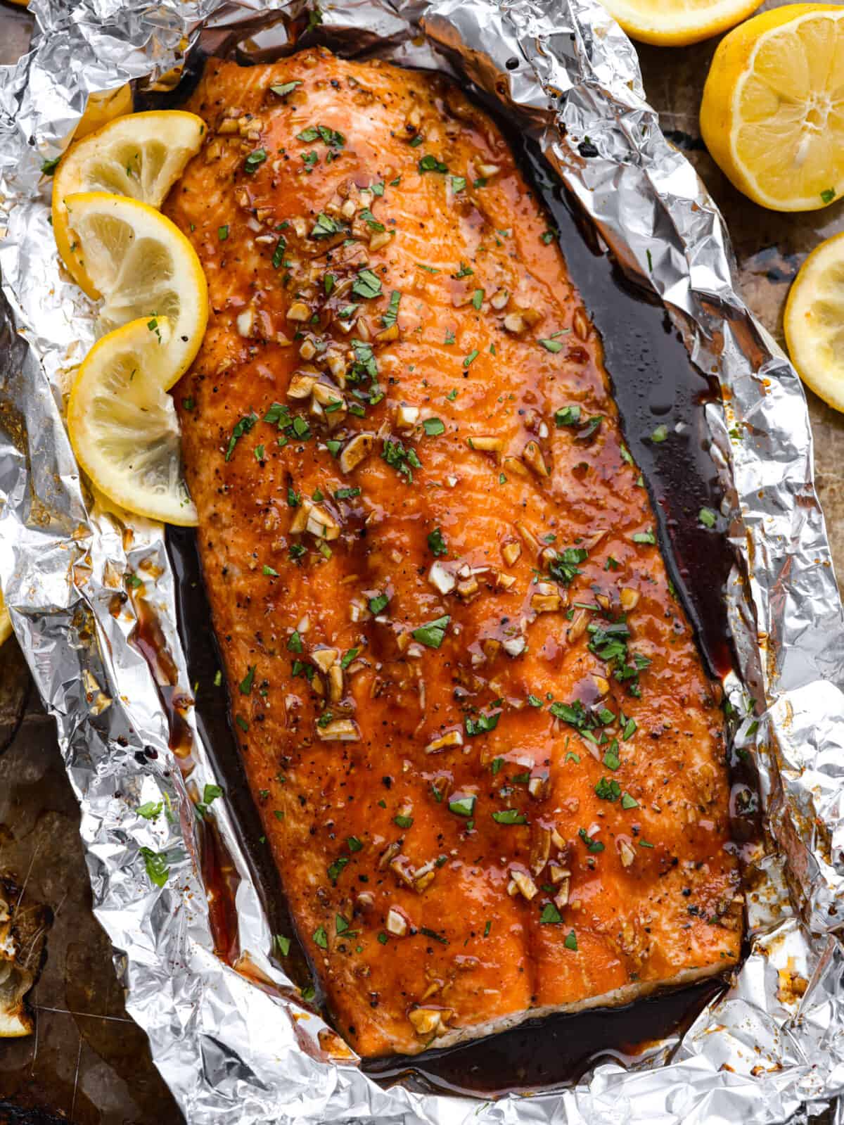 Salmon wrapped in foil and garnished with lemon slices.