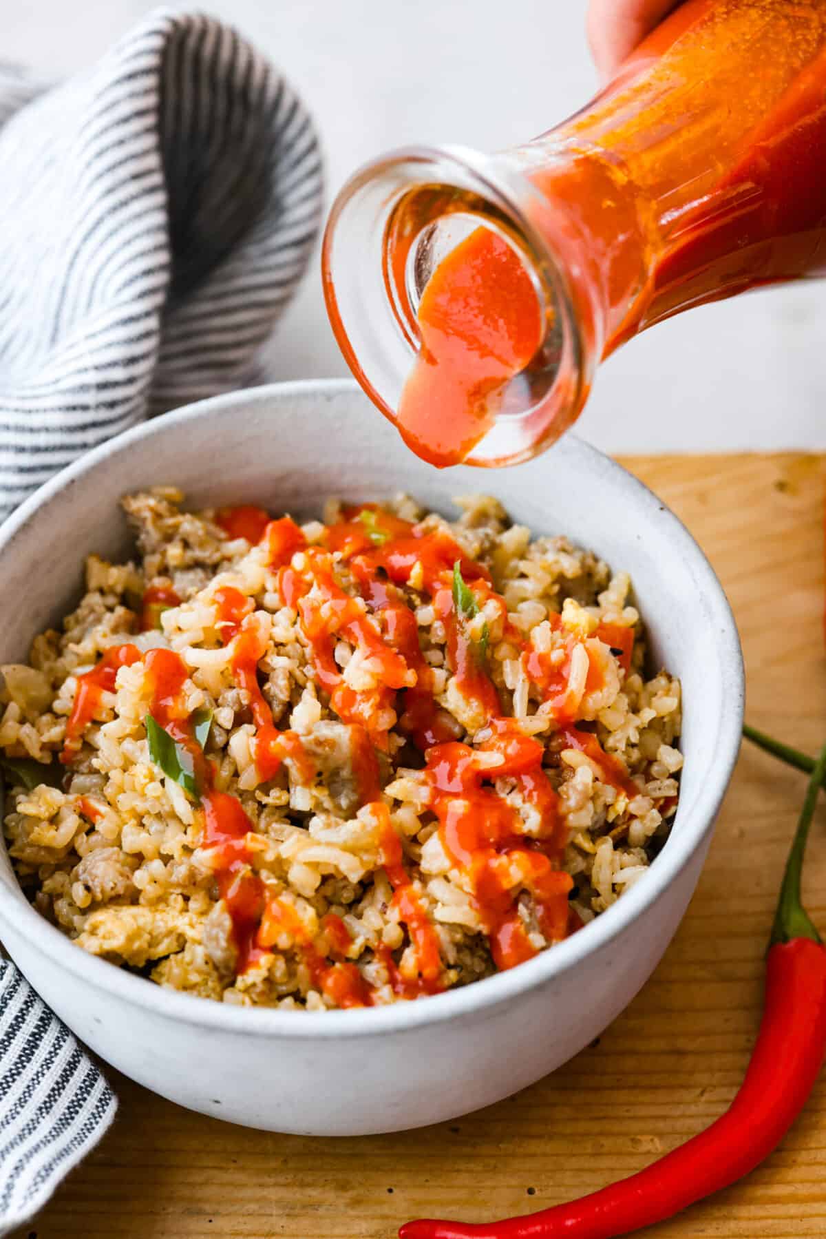 Adding a drizzle of sriracha to fried rice.