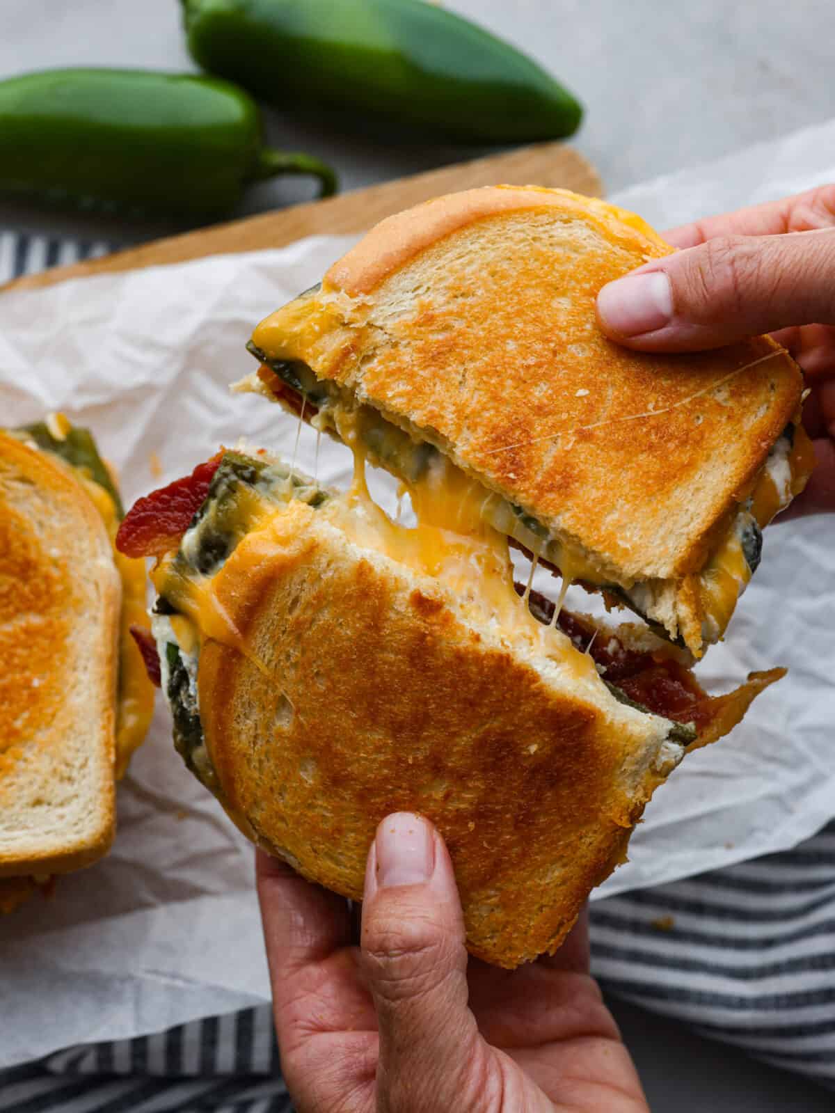 Two halves of a jalapeno grilled cheese being pulled apart.