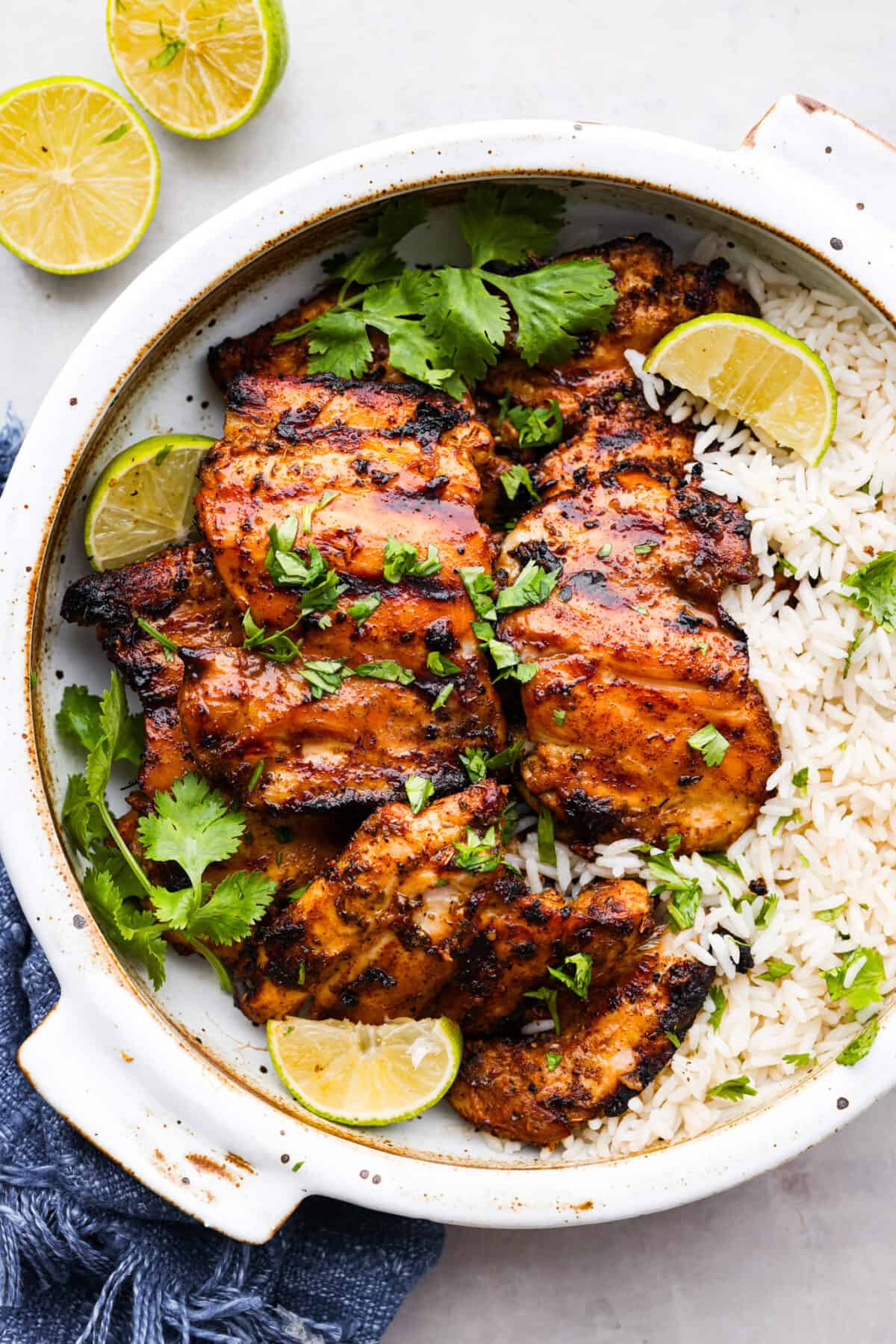 Serve Mexican grilled chicken over rice. Garnished with fresh herbs and lime slices.