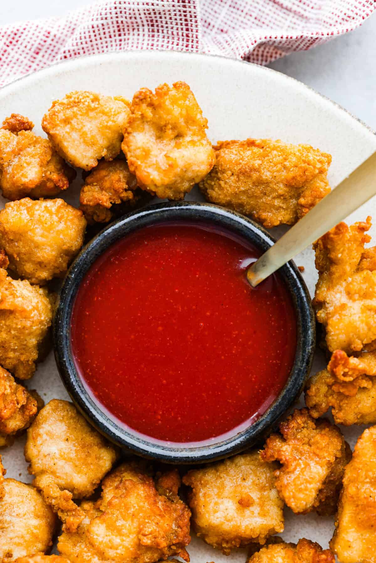 A bowl of polynesian sauce surrounded by chicken nuggets.