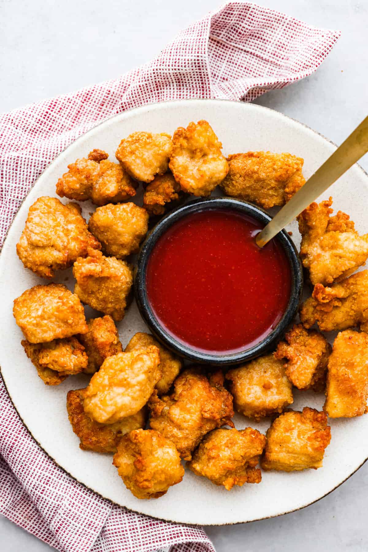 Top-down view of sauce and chicken nuggets on a white plate.