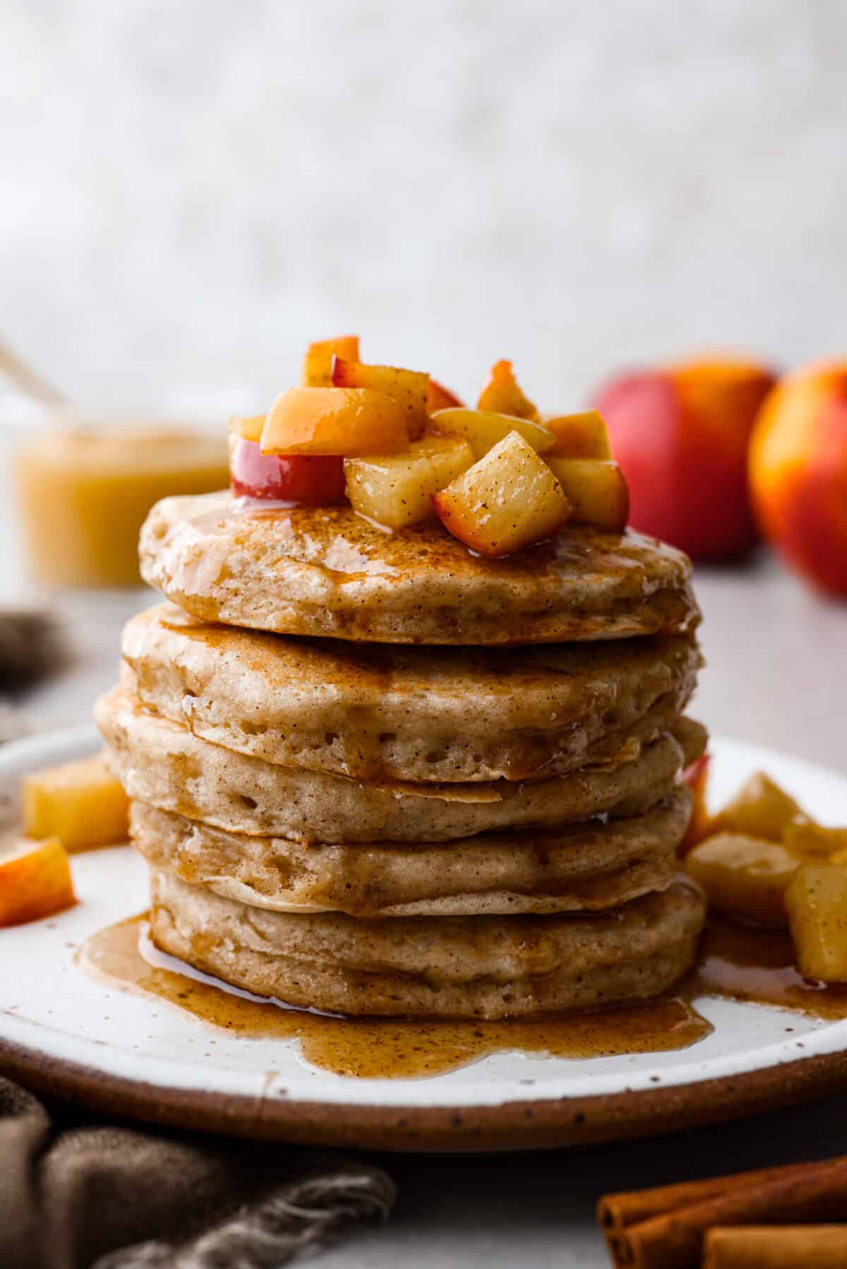 Close view of applesauce pancakes with sauteed apples and syrup on top.