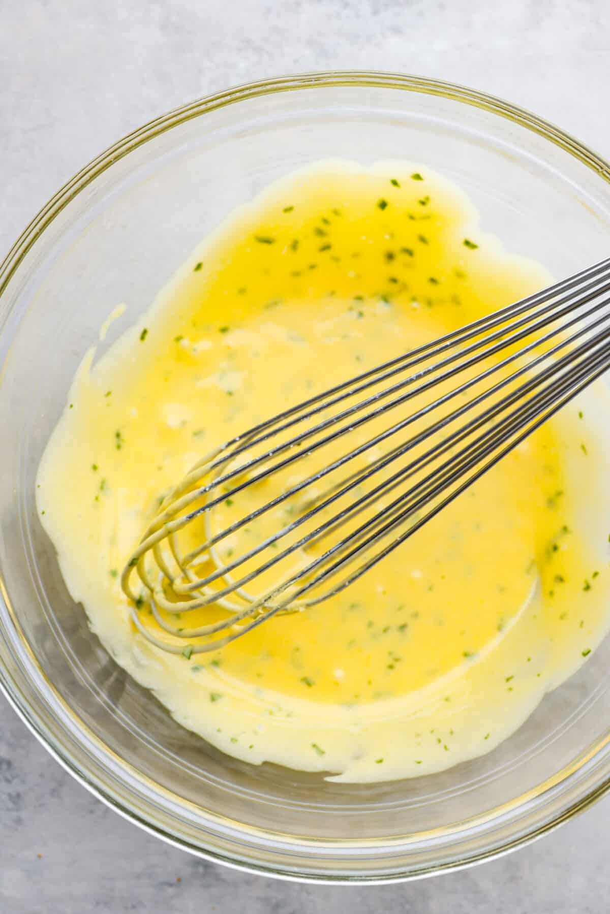 Bearnaise sauce in a glass bowl, being whisked together.