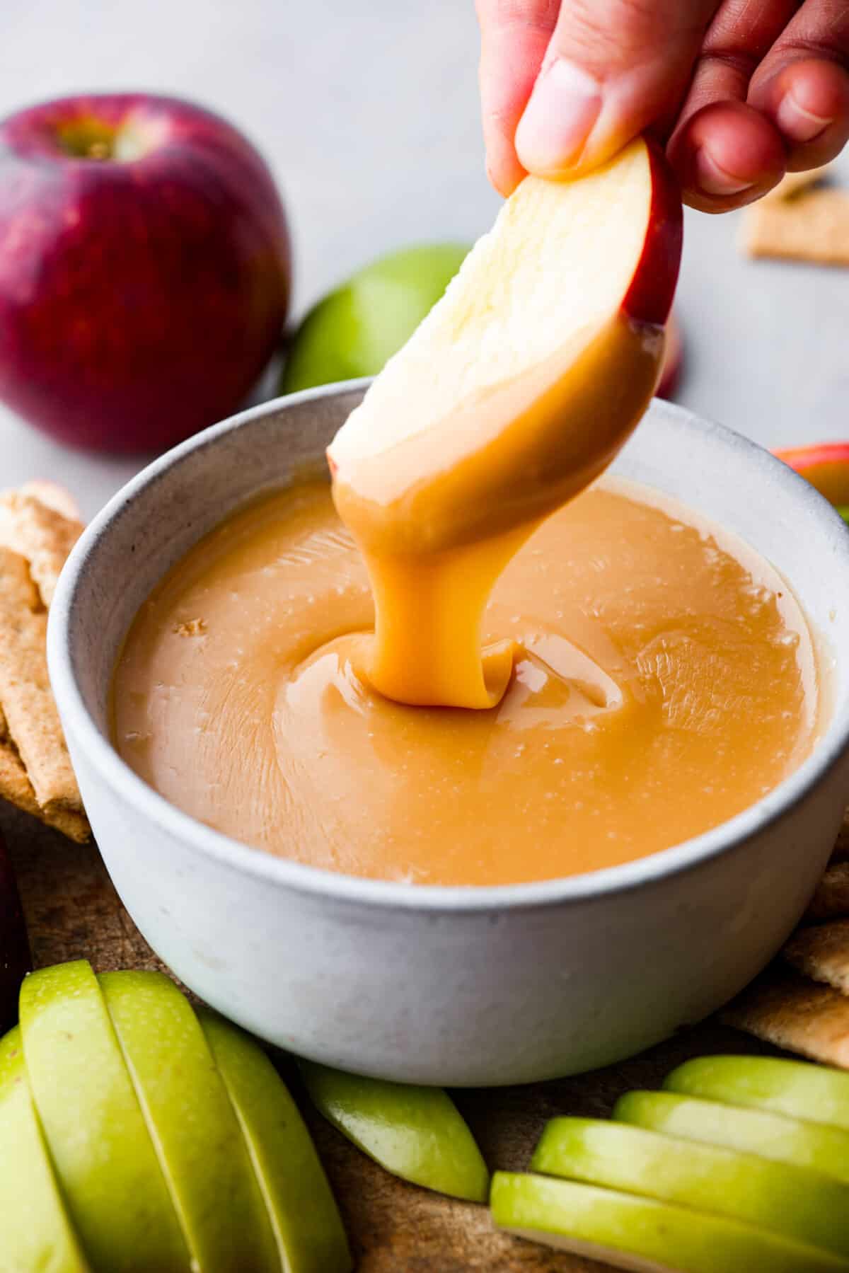 Closeup of caramel apple dip and an apple slice.