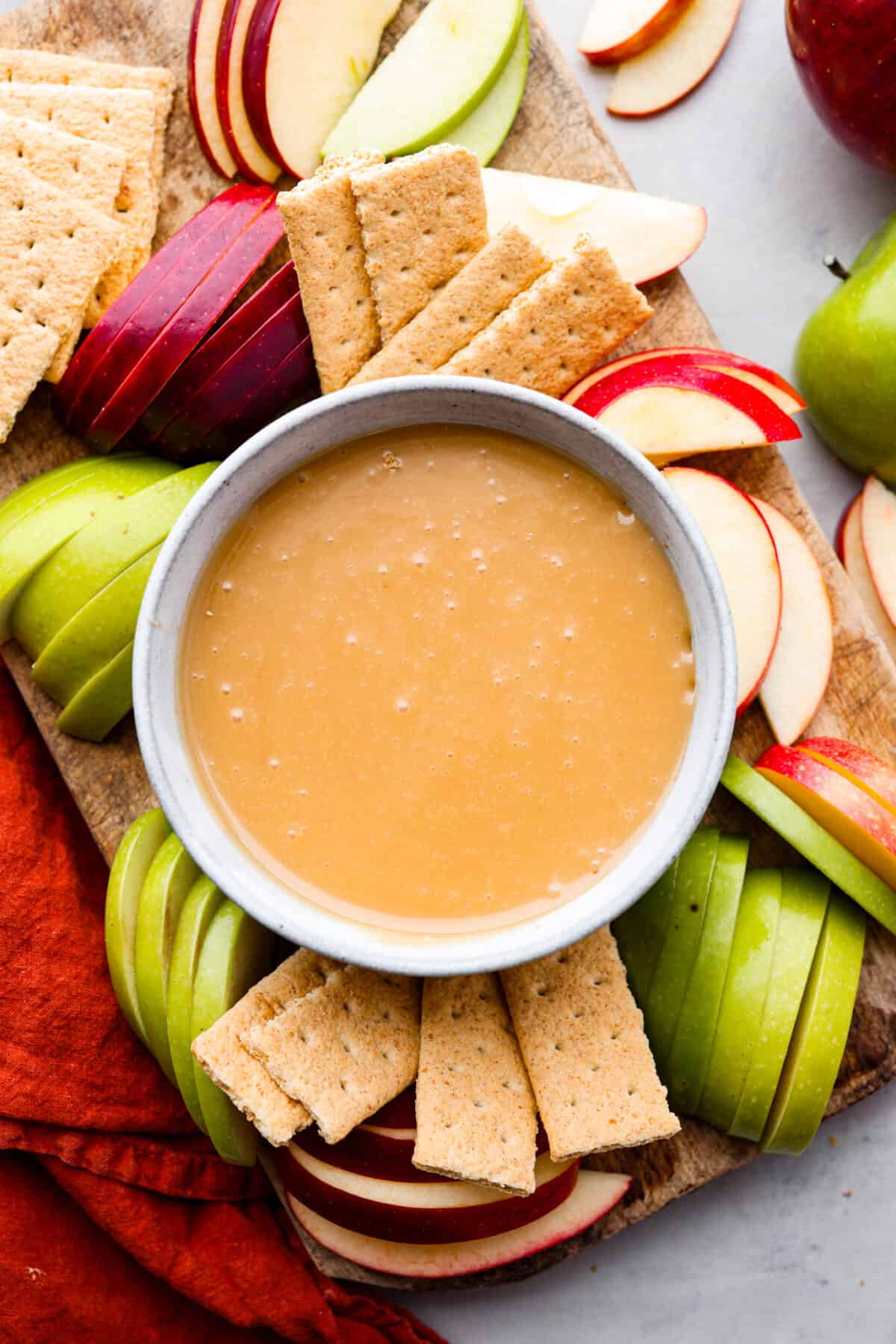 A bowl of caramel apple dip served with sliced apples and graham crackers.