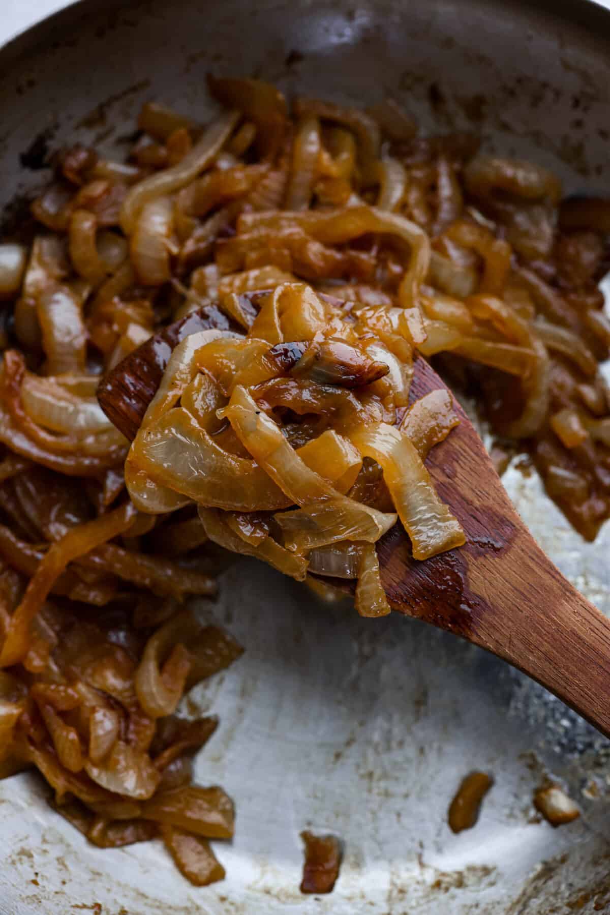 Closeup of caramelized onions on a wooden spoon.