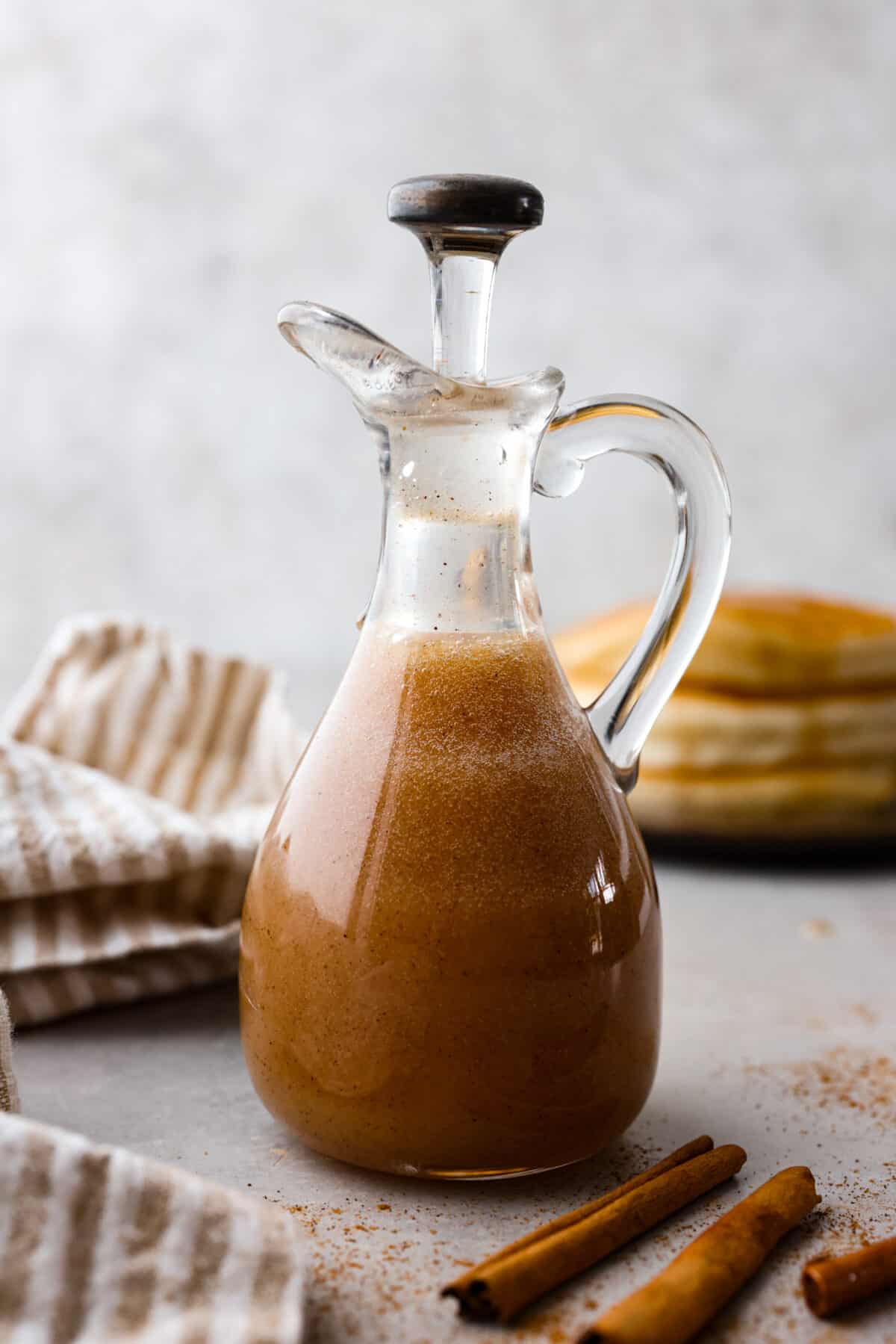 Side shot of cinnamon syrup in small glass container.