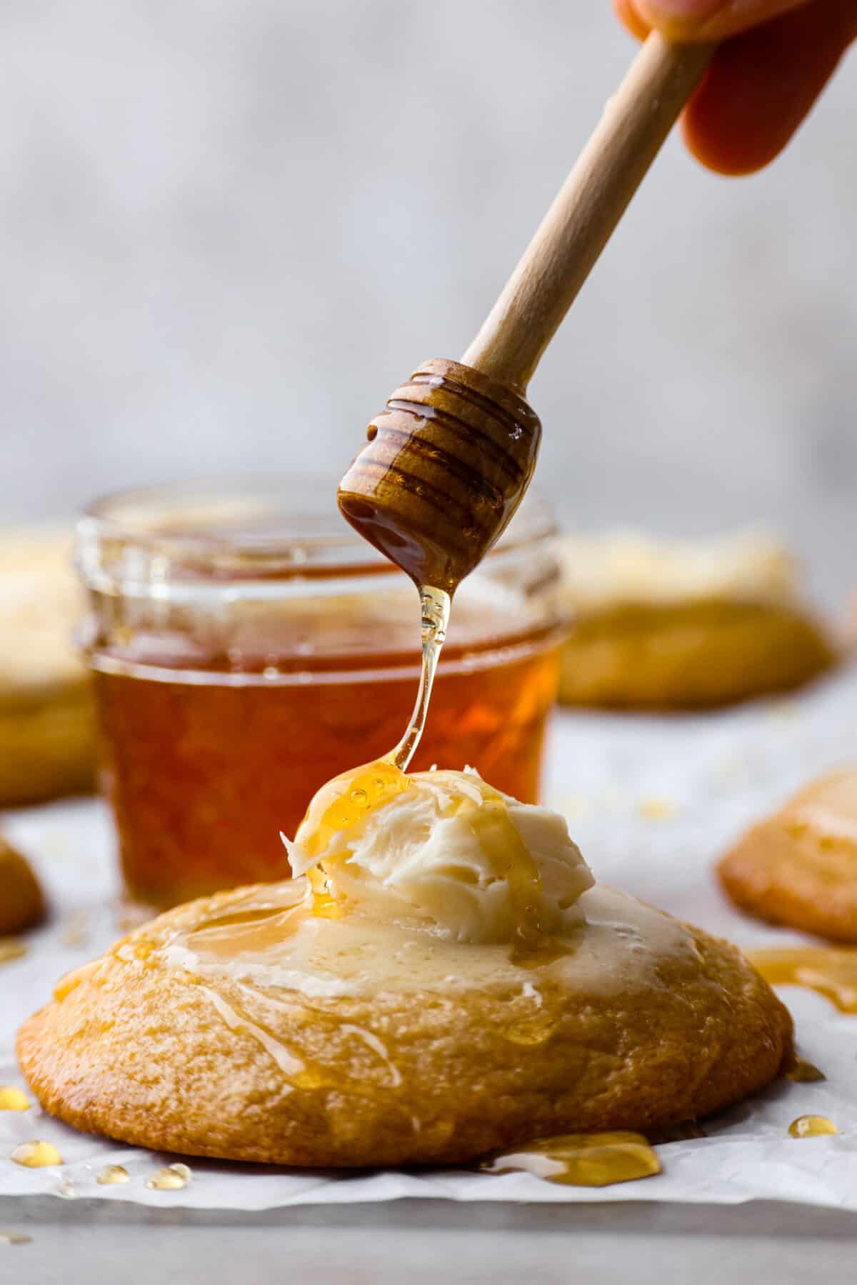 Close view of honey drizzling on a cornbread cookie on top of the honey butter frosting.